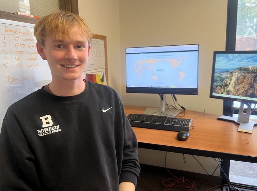 Ben Bockmann, Bowdoin student employee, sitting next to a computer displaying his ILL homepage